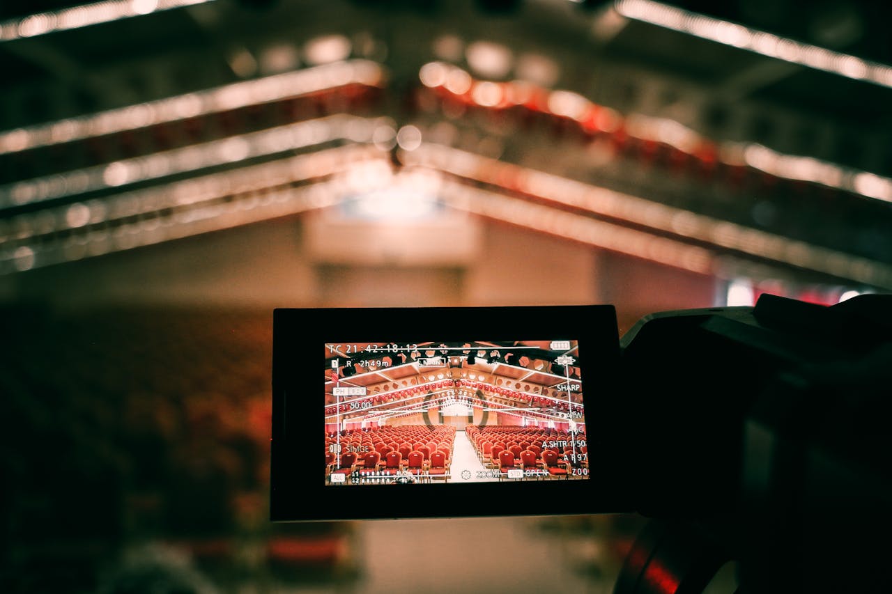 A digital camera screen captures an empty auditorium with rows of red seats under warm lighting.