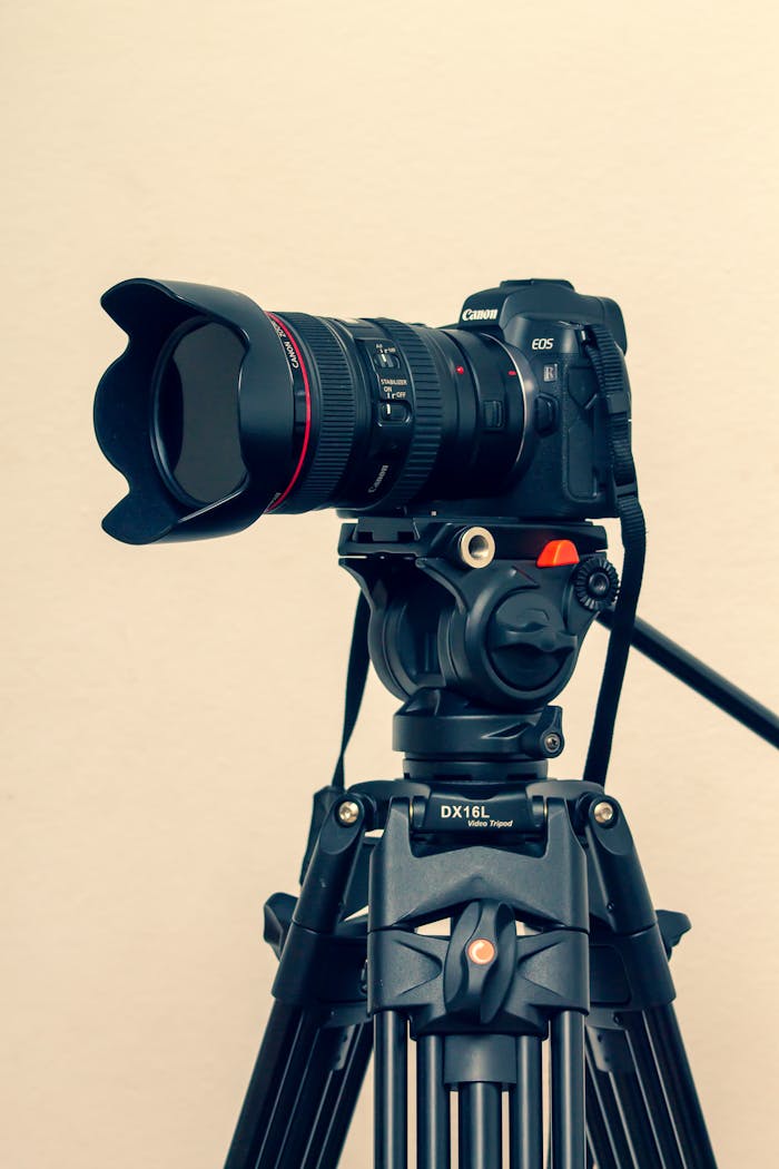 gallery-5 Close-up of a professional DSLR camera mounted on a tripod with a lens hood.