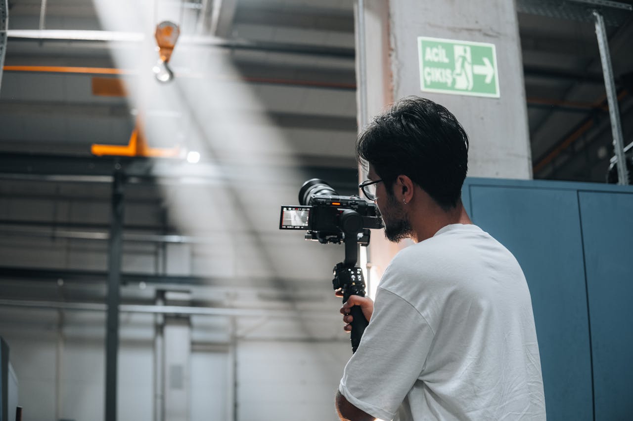 gallery-1 Cameraman using a gimbal to record a scene in an industrial interior space.